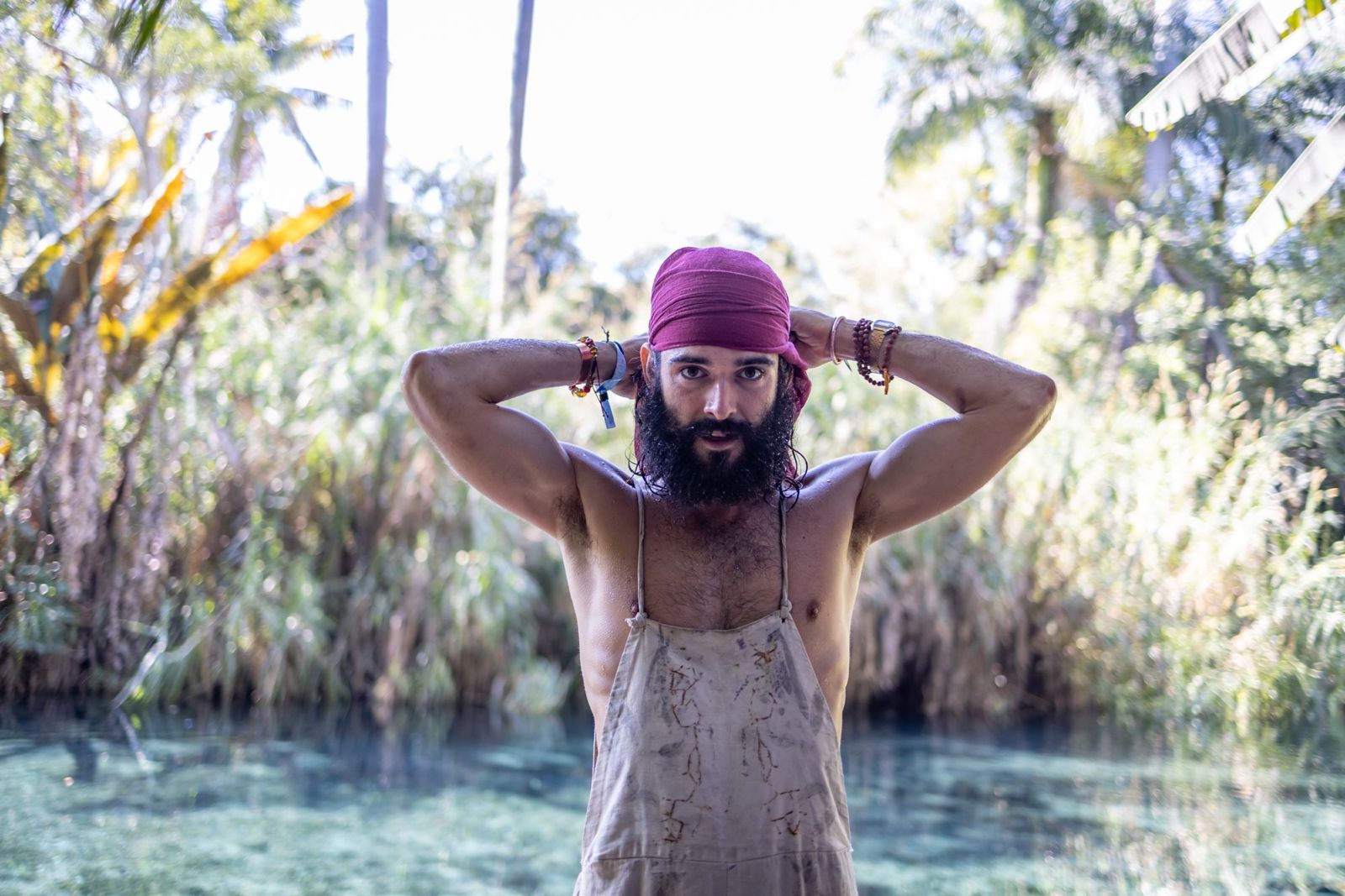 Atabey standing in a still pool surrounded by jungle
